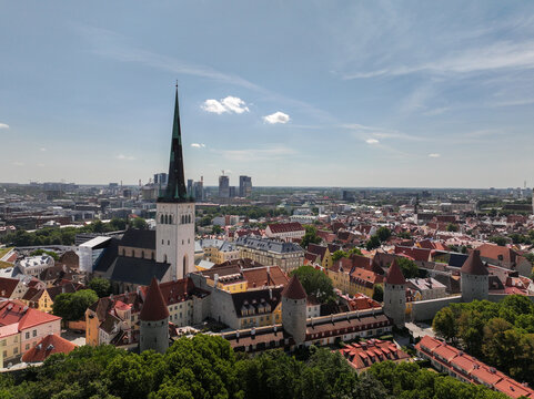 Aerial view of St. Olaf's Church and the historic old town of Tallinn with medieval stone walls, red-tiled rooftops, and a modern skyline in Tallinn, Harju County, Estonia.