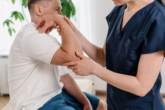 Physiotherapist works with patient on joint during rehabilitation session in clinic