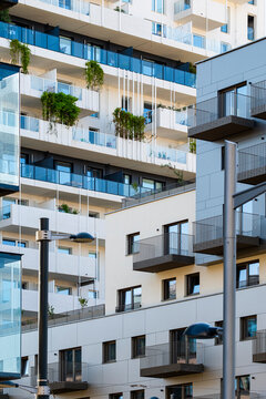 Contemporary apartments in Nordbahnviertel, Vienna, Austria, rise above the street through a vertical facade as glass balconies frame terraces edged by greenery.