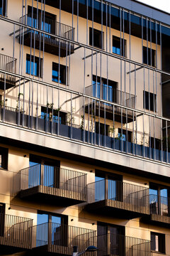 Across a warm apartment facade, sunlight moves through railings while balconies cast shadows in measured repetition throughout Nordbahnviertel, Vienna, Austria.