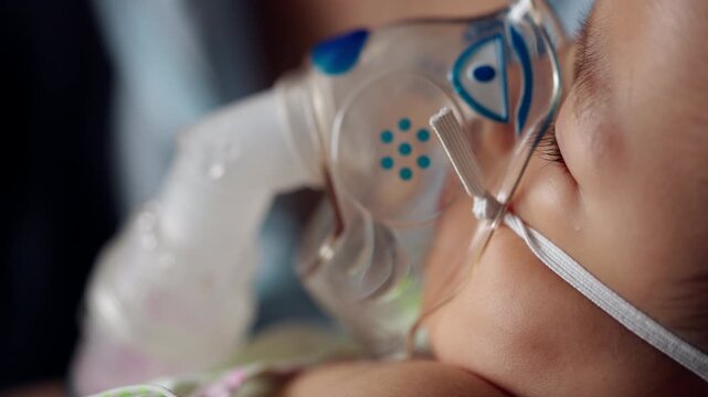 Close-up of a sick infant receiving nebulizer breathing treatment while resting in a caregiver's arms, representing pediatric respiratory therapy, medical support, and recovery.