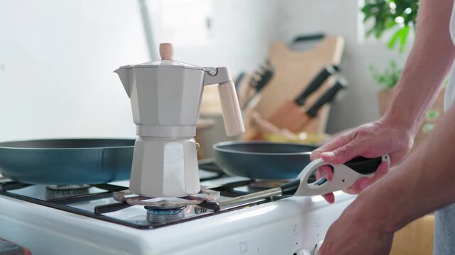 Man's hands lighting a gas stove with a long lighter and placing a moka pot on the burner to brew coffee, representing a cozy morning ritual and a comfortable home wellbeing lifestyle