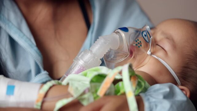Parent comforts a sleeping baby boy during respiratory inhalation treatment, highlighting family support, pediatric healthcare, nebulizer therapy, illness management, and hospital care.