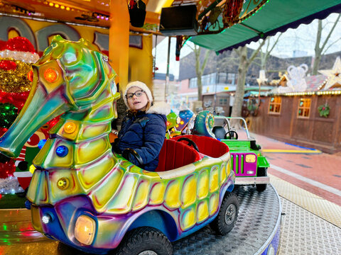 Little preschool girl riding on a merry go round carousel horse at Christmas funfair or market, outdoors. Happy child having fun on traditional family xmas market in Cologne, Germany