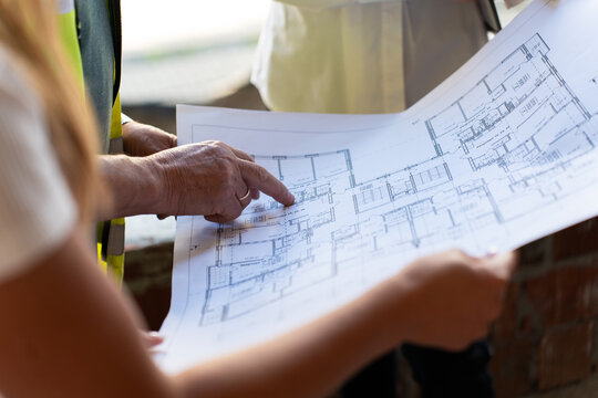 Workers study sketch of project observing proportions. Employees examine blueprint sketch interpreting symbols and notes marked by architect