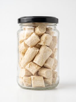 Jar of raw sliced horseradish root on white background