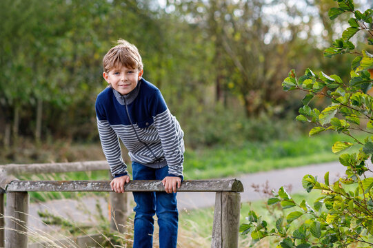 Smiling schoolboy leaning forward outdoors in a park with a cheerful expression and natural background