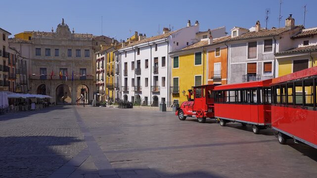 Red tourist train parked at Plaza Mayor with the historic city hall in Cuenca Spain