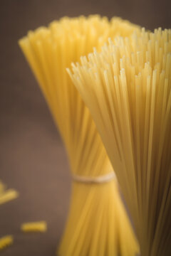 Bunch of raw spaghetti pasta close up standing vertically on dark background