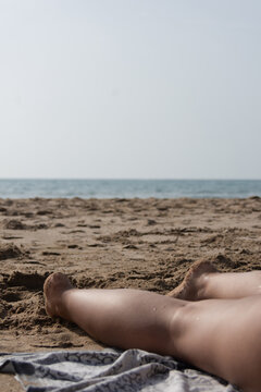 Vertical close up of woman relaxing on sandy beach