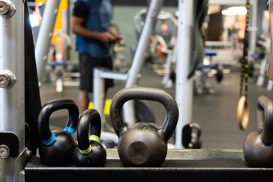 Kettlebells in modern gym with fitness equipment and blurred athlete in background, strength training and functional workout concept