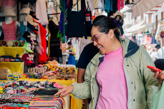 A woman examines handicraft items on display at an open air market.