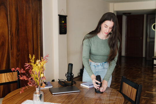 Woman preparing electronic equipment for a podcast.