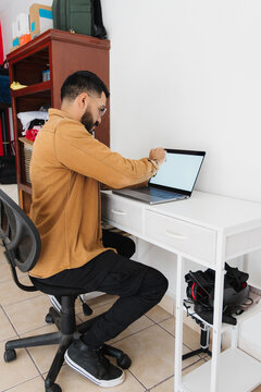 Bearded, bespectacled adult, cleaning his laptop screen.