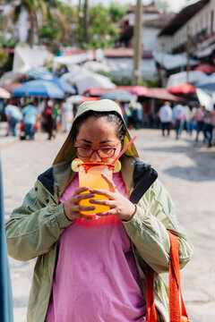 A woman holds a drink at an outdoor market.