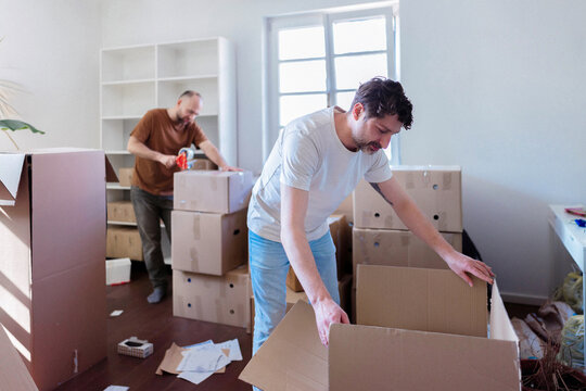 Friends Packing Boxes During Moving Day At Home