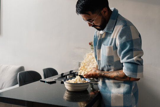 Man pouring popcorn in kitchen