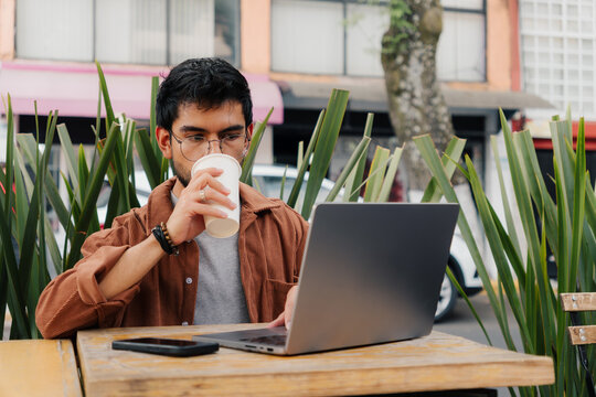 Entrepreneur drinking coffee while working on his laptop.
