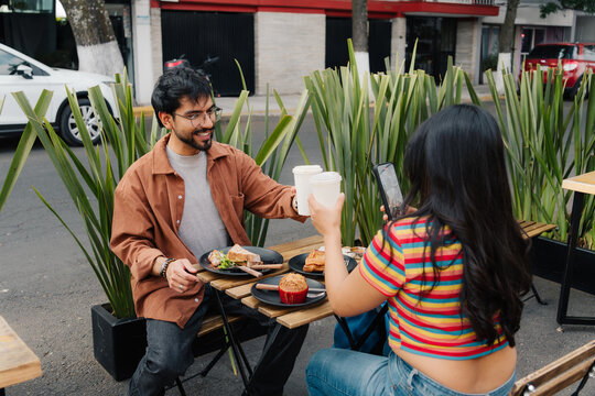 Young couple toasting with coffee on an urban terrace.