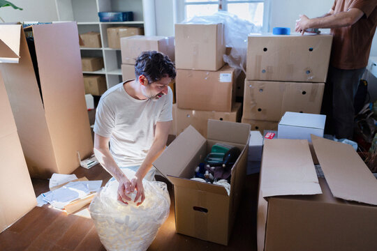 Man Packing Boxes During Moving Day At Home