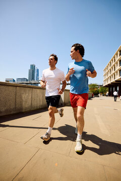 Men Run Together on a Sunny Promenade in London