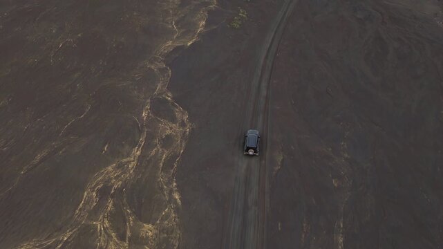 Aerial view of vehicle on gravel road through Iceland Highlands lava feilds