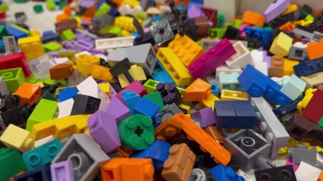 High angle view of LEGO plastic construction bricks on a building plate. Various colorful LEGO building bricks attached to a grey baseplate table in a playroom. 