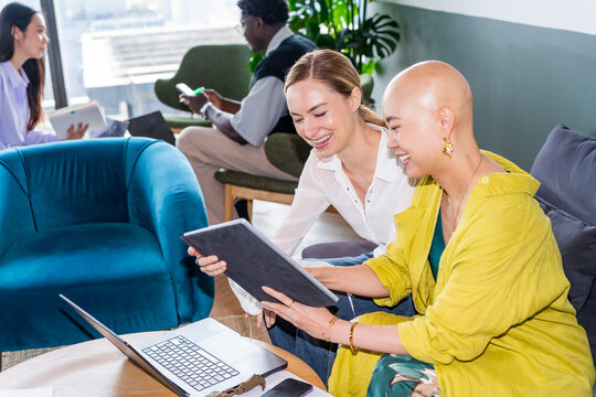 Two Women Share a Tablet in a Modern Office During the Day