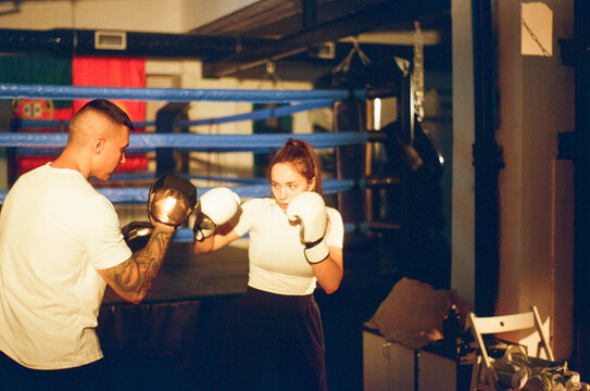 Female boxer practices strikes with trainer in gym. Woman Power
