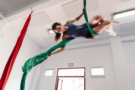 Woman exercising aerial silk acrobatics in training studio