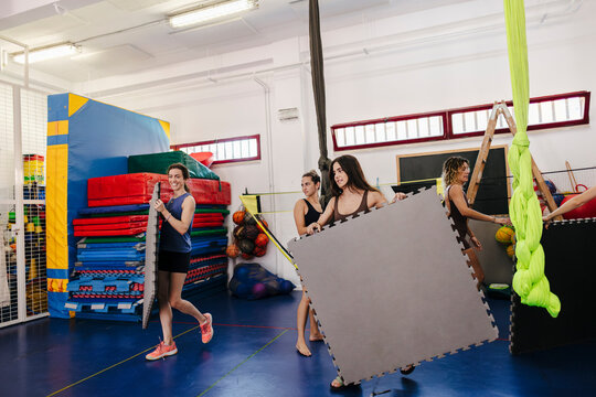 Young women setting up interlocking foam mats in gym