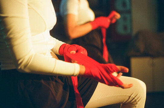 Female boxers wrap hands with strips indoors