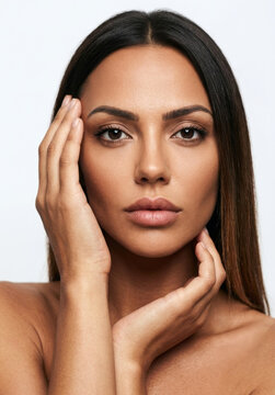Close-up beauty portrait of gorgeous woman framing her face with hands on white background.