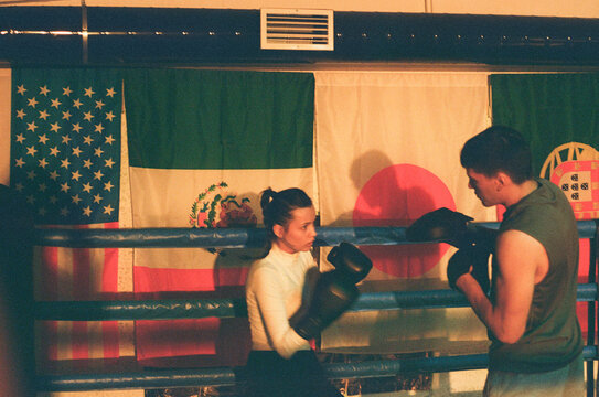 Boxer woman fights with coach using mitt pads during workout.