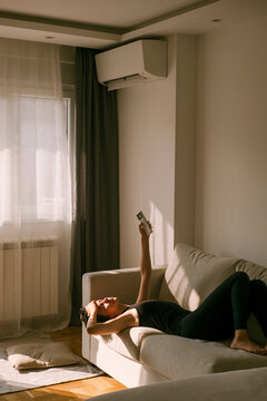 Person Relaxing on a Couch While Holding a AC Remote Control