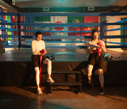Boxers women uwrap hands with bandage in boxing gym before fight