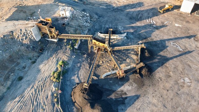 Aerial view of a mining site on the Black Sea coast featuring industrial conveyor belts, piles of dark excavated material, and a truck in Istanbul, Turkey.