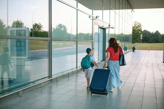 Mother and son walking with luggage on airport 