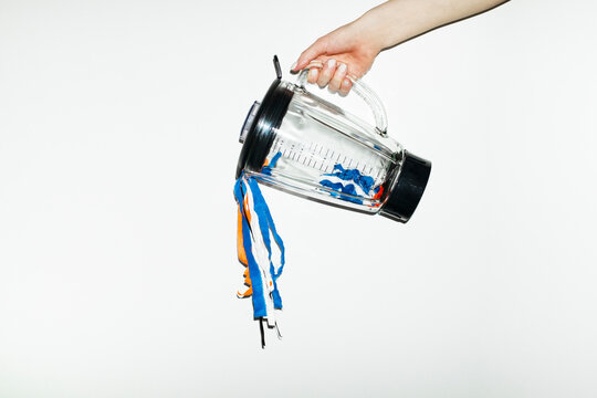 Hand holding blender and pouring colourful curly party laces 