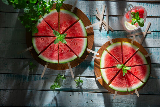 Watermelon slices on sticks with mint on table