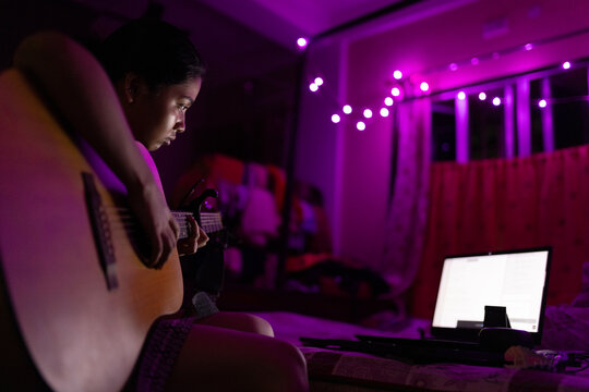 Indian young woman playing guitar and learning singing