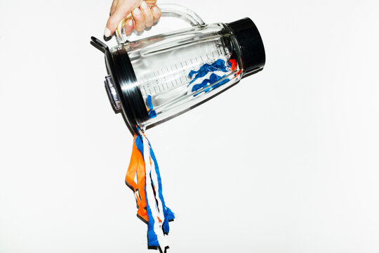 Hand holding blender and pouring colourful curly party laces 