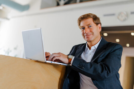 Business professional smiling while working on laptop