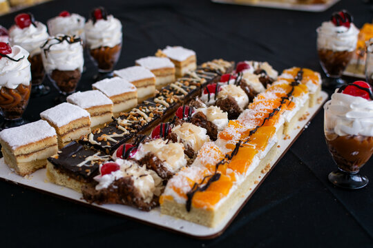 Amplia variedad de postres en un evento. Bandeja de mini pasteles surtidos y shots dulces de dulce de leche y crema. Opciones de mesa dulce.
