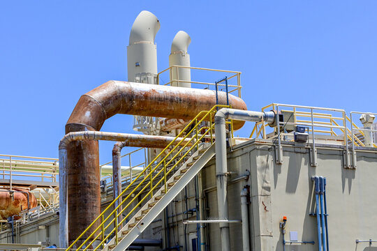 Industrial processing facility with pipelines, ventilation stacks, and service platforms, illustrating manufacturing infrastructure, process engineering, and industrial operations