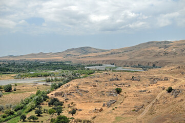 Ancient stone ruins of Uplistsikhe archaeological site overlooking the Mtkvari River valley and dry hills in Georgia © MikhailT
