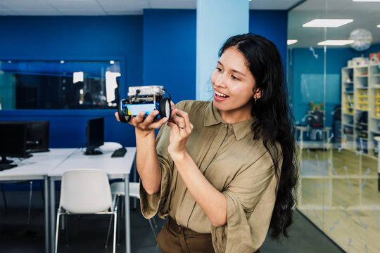 latina young university woman student working on a robotics project and car robotics in classroom. Hispanic girl in technology class in an Academic Environment in Latin America