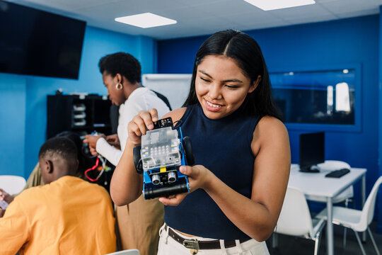latina young university woman student working on a robotics project and car robotics in classroom. Hispanic girl in technology class in an Academic Environment in Latin America