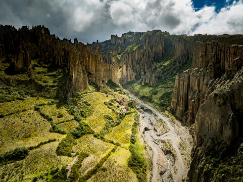 Aerial view of Valle de las Animas featuring rock spires, rugged cliffs, and a winding dry riverbed surrounded by green slopes in La Paz, Departamento de La Paz, Bolivia.