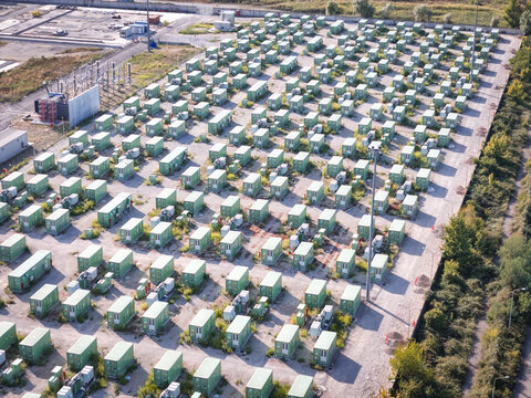Aerial view of rows of green battery storage containers arranged in a grid pattern at the energy transition site in Trino, Piedmont, Italy.